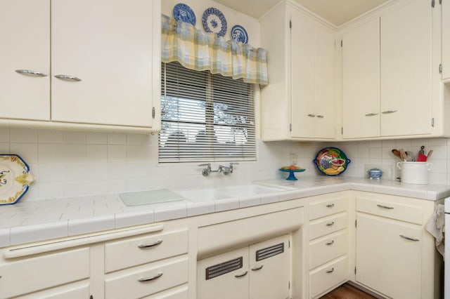 kitchen featuring tasteful backsplash, sink, tile counters, and white cabinets