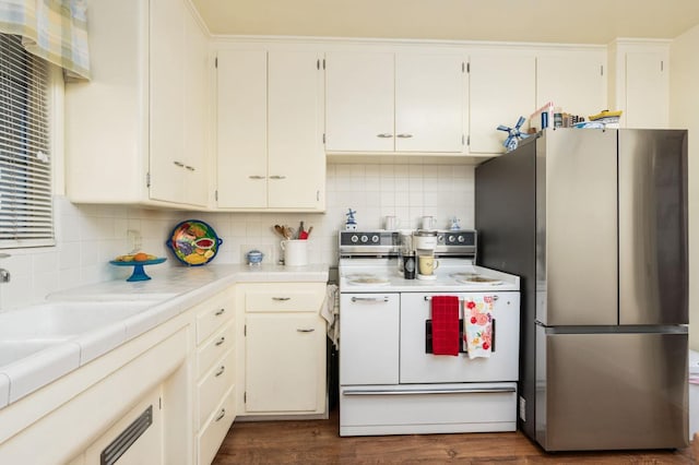 kitchen with electric stove, decorative backsplash, stainless steel fridge, and tile countertops