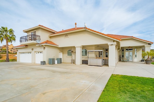 exterior space featuring central AC unit, a garage, and a balcony