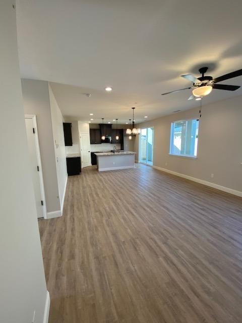 unfurnished living room with dark hardwood / wood-style flooring and ceiling fan with notable chandelier