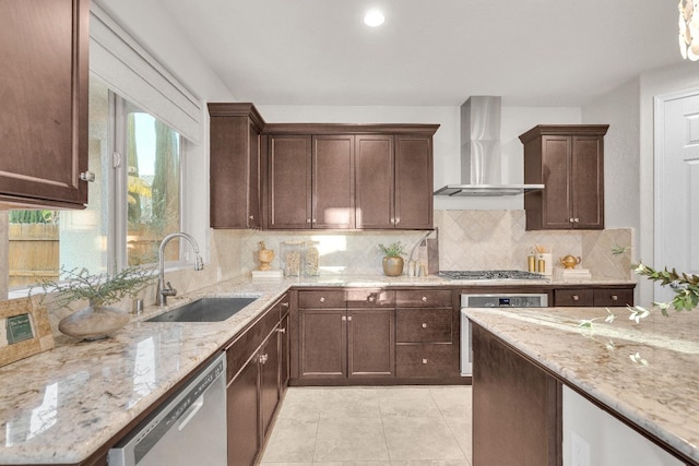 kitchen with wall chimney exhaust hood, sink, appliances with stainless steel finishes, light stone countertops, and backsplash