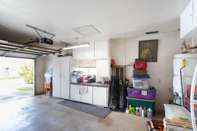 garage featuring gas water heater, visible vents, and a garage door opener