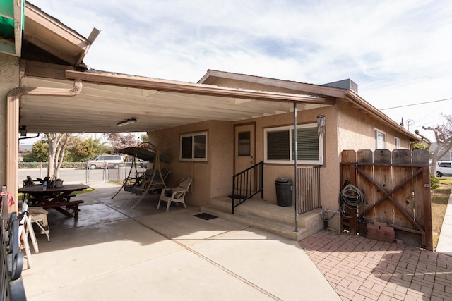 view of patio / terrace featuring a carport, a gate, driveway, and fence