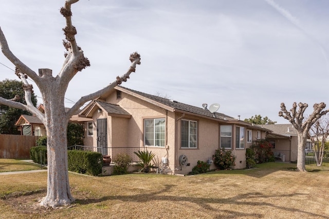 view of front of property featuring fence, a front lawn, and stucco siding