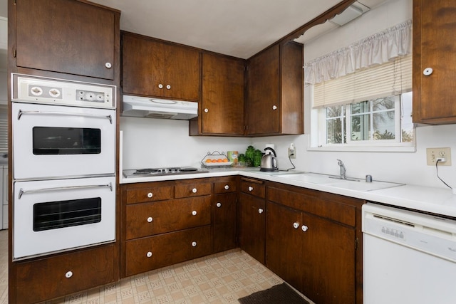 kitchen with white appliances, light countertops, a sink, and under cabinet range hood