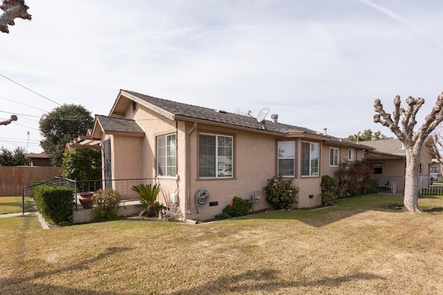 view of home's exterior featuring a yard, fence, and stucco siding