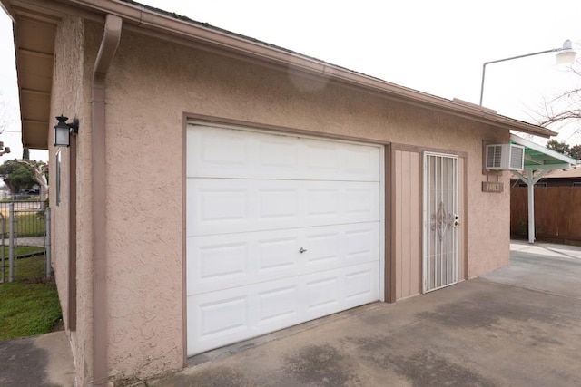 garage with an AC wall unit and fence