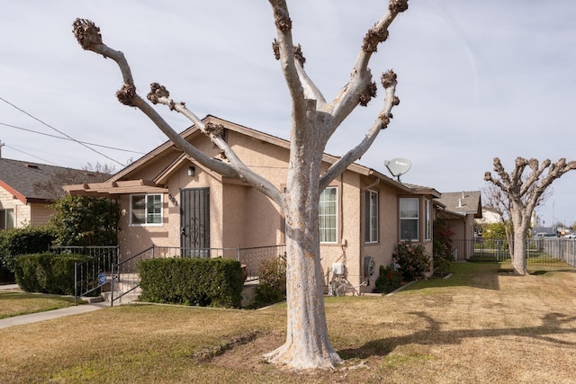 view of front of home with a front yard, fence, and stucco siding