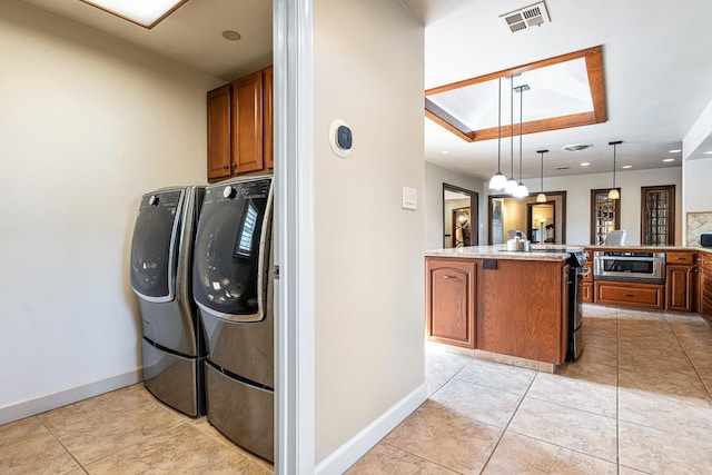 clothes washing area with cabinets, independent washer and dryer, and light tile patterned floors