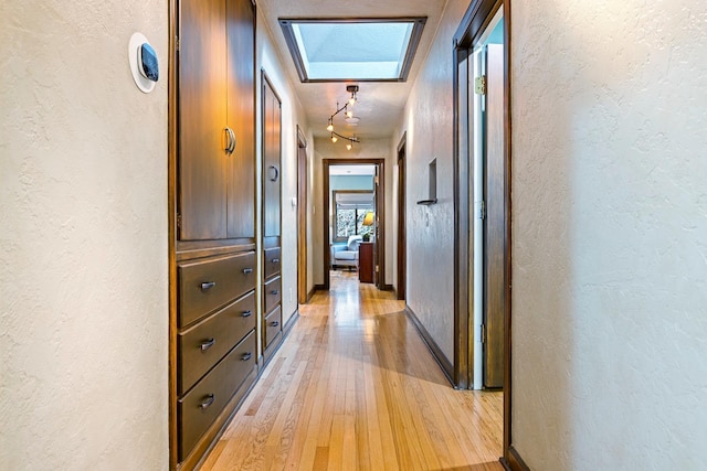 corridor with a skylight and light hardwood / wood-style flooring