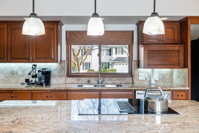 kitchen with dishwashing machine, sink, hanging light fixtures, light stone counters, and decorative backsplash