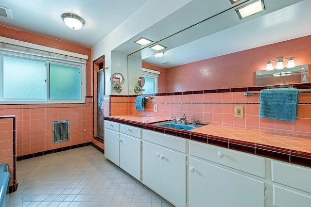 bathroom with tile patterned floors, plenty of natural light, tile walls, and vanity