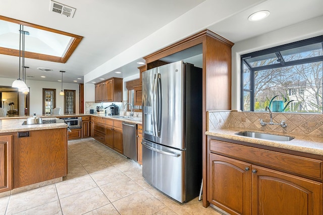 kitchen with tasteful backsplash, appliances with stainless steel finishes, sink, and hanging light fixtures