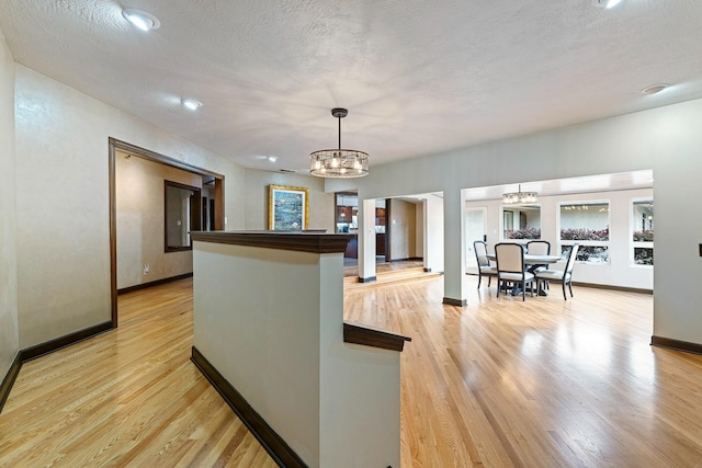 kitchen with pendant lighting, a textured ceiling, light hardwood / wood-style floors, and a chandelier