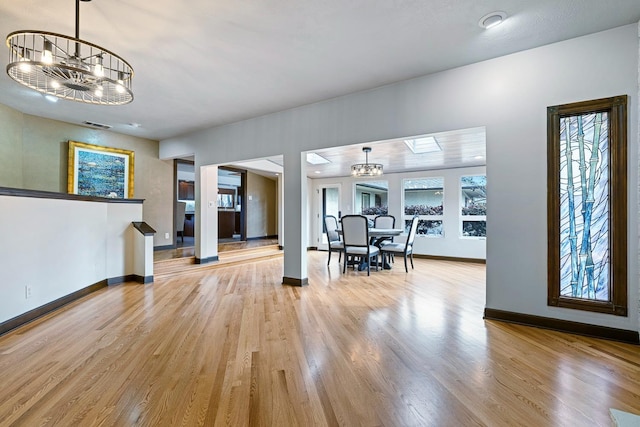 unfurnished dining area with an inviting chandelier and light hardwood / wood-style flooring