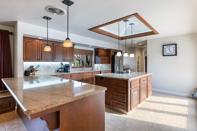 kitchen with tasteful backsplash, decorative light fixtures, sink, and a kitchen island