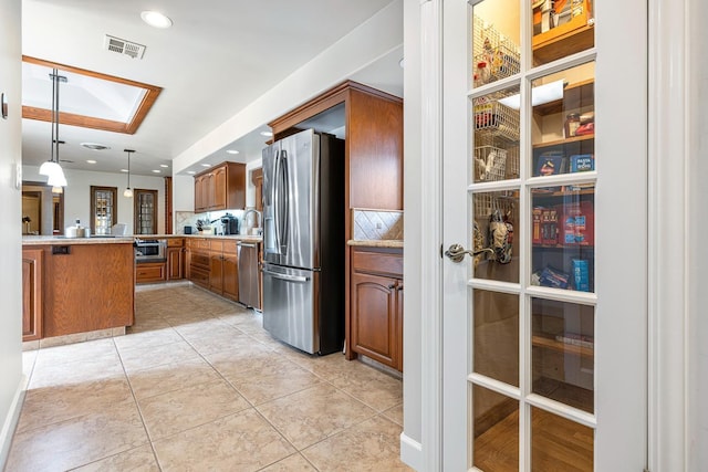 kitchen featuring pendant lighting, appliances with stainless steel finishes, kitchen peninsula, and light tile patterned flooring