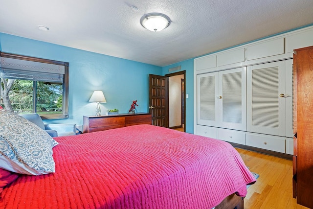 bedroom featuring light hardwood / wood-style floors, a closet, and a textured ceiling