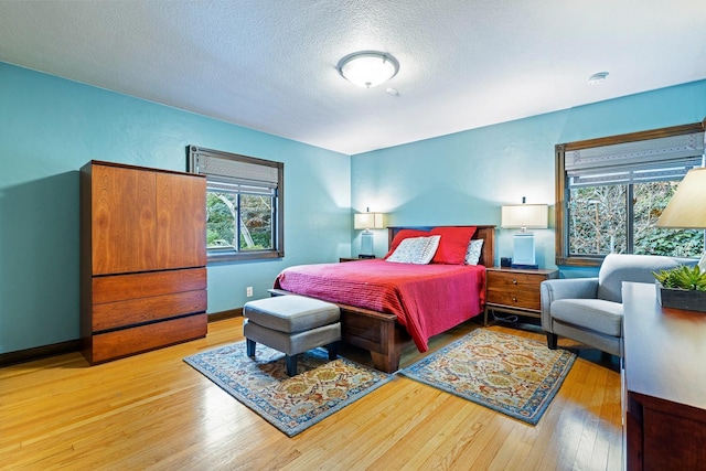 bedroom with a textured ceiling and light hardwood / wood-style flooring