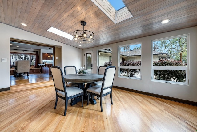 dining space with an inviting chandelier, vaulted ceiling with skylight, wooden ceiling, and light hardwood / wood-style floors