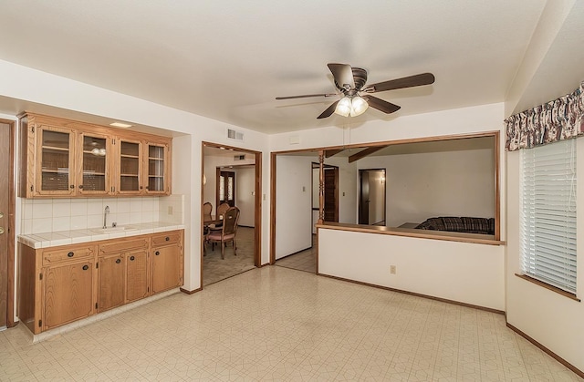 kitchen featuring sink, tile countertops, ceiling fan, and decorative backsplash