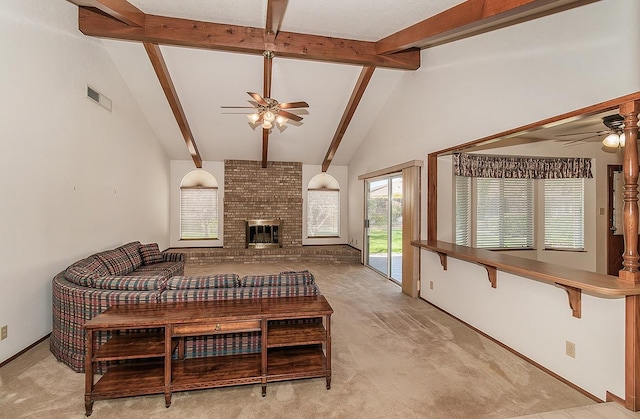 living room with beamed ceiling, a brick fireplace, light colored carpet, and ceiling fan