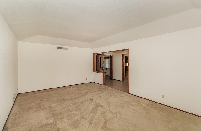 spare room featuring lofted ceiling, a textured ceiling, and carpet