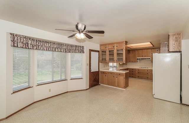 kitchen with tasteful backsplash, a skylight, kitchen peninsula, white fridge, and ceiling fan