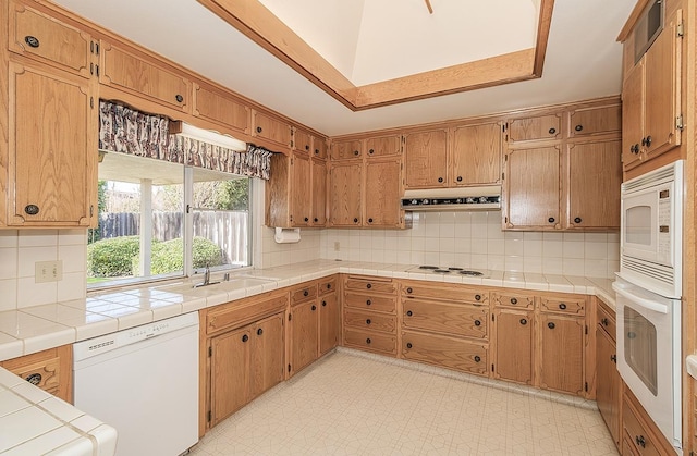 kitchen with sink, tile countertops, white appliances, and decorative backsplash