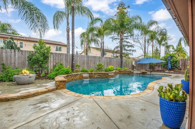 view of pool with a fenced backyard, a pool with connected hot tub, a fire pit, and a patio