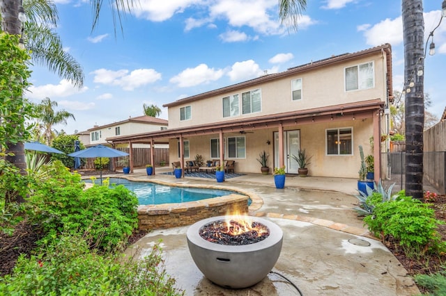 back of house featuring stucco siding, fence private yard, a fire pit, and a patio