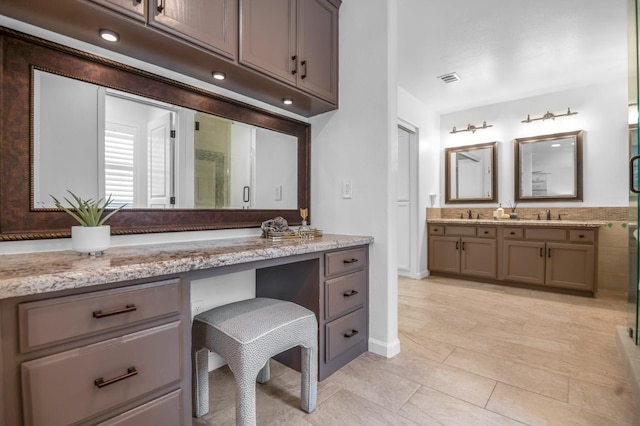 bathroom with double vanity, visible vents, a stall shower, and a sink