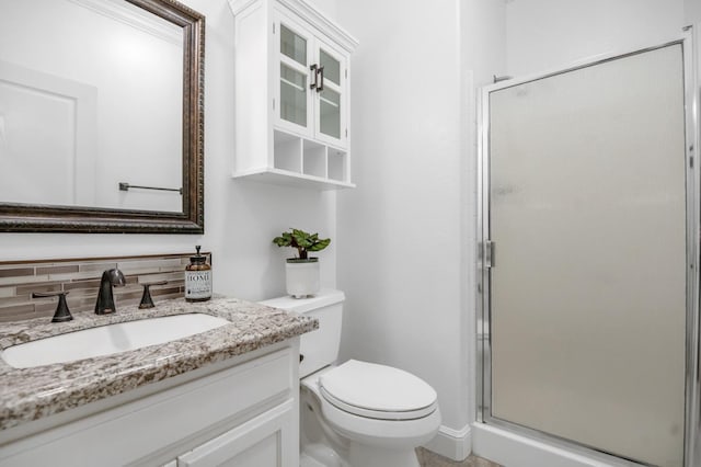 bathroom featuring tasteful backsplash, a stall shower, toilet, and vanity