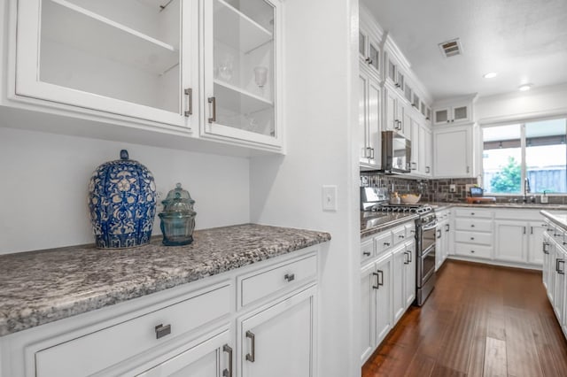 kitchen with dark wood-style floors, visible vents, white cabinets, appliances with stainless steel finishes, and tasteful backsplash