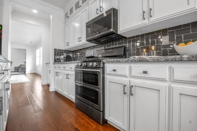 kitchen featuring tasteful backsplash, white cabinetry, appliances with stainless steel finishes, stone counters, and dark wood-style flooring