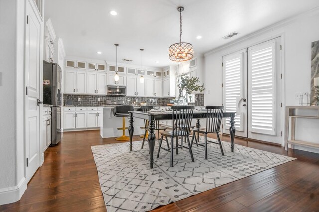 dining area featuring dark wood-style floors, visible vents, a chandelier, and crown molding
