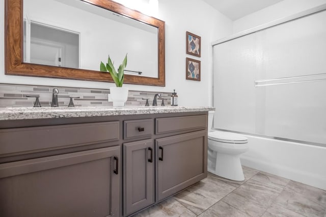 bathroom featuring double vanity, toilet, bath / shower combo with glass door, and a sink