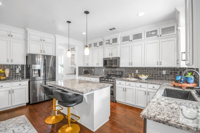 kitchen with a sink, white cabinets, dark wood finished floors, and stainless steel appliances