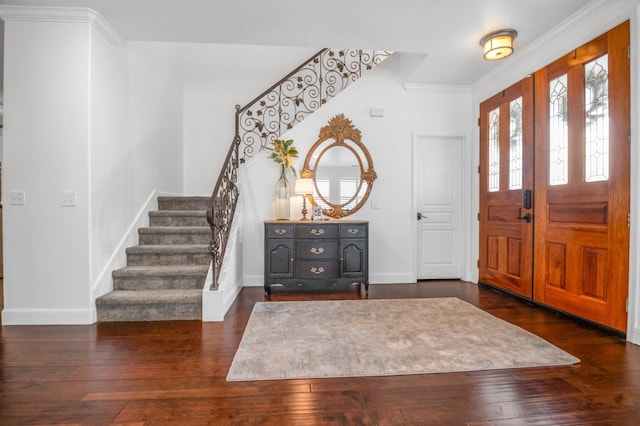 foyer entrance with dark wood finished floors, crown molding, stairs, and baseboards