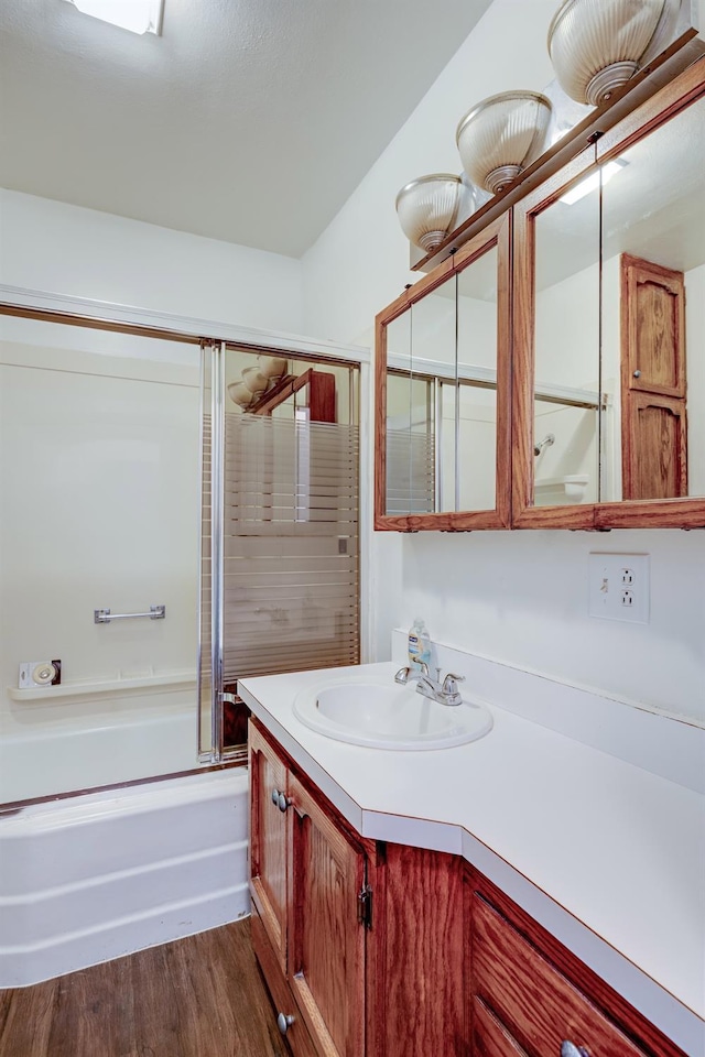 bathroom with wood-type flooring, bath / shower combo with glass door, and vanity