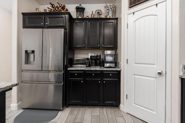 kitchen with light stone counters and stainless steel fridge