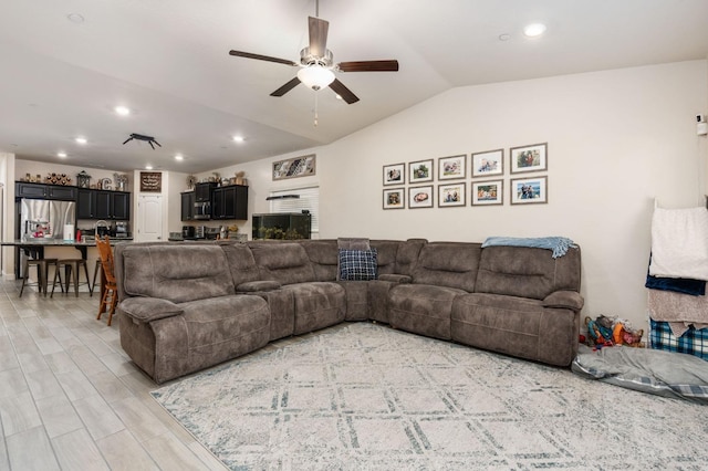 living room featuring lofted ceiling, ceiling fan, and light wood-type flooring