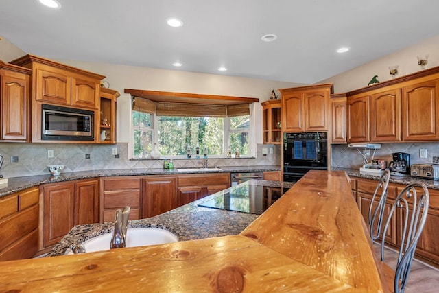 kitchen with tasteful backsplash, dark stone countertops, and black appliances