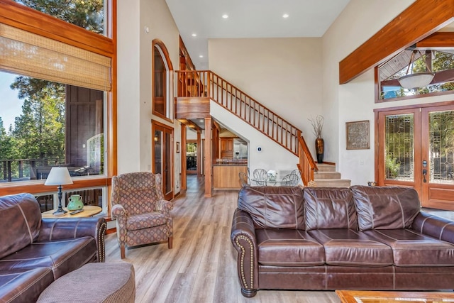 living room featuring french doors, light wood-type flooring, and a high ceiling