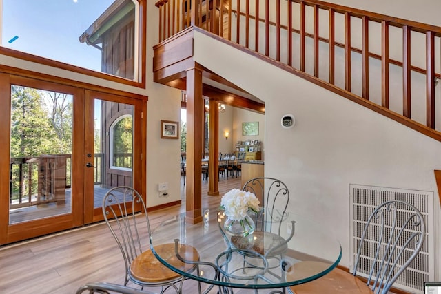 dining room with french doors, plenty of natural light, light hardwood / wood-style floors, and a high ceiling