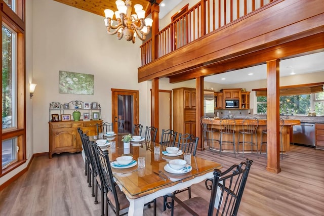 dining space with an inviting chandelier, a high ceiling, and light wood-type flooring