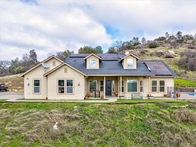 view of front of home with a front lawn, a patio area, and solar panels