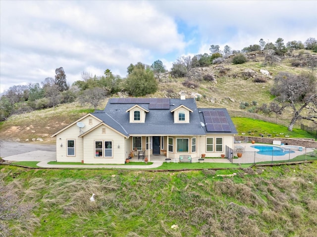 rear view of house with a patio area, solar panels, and a lawn