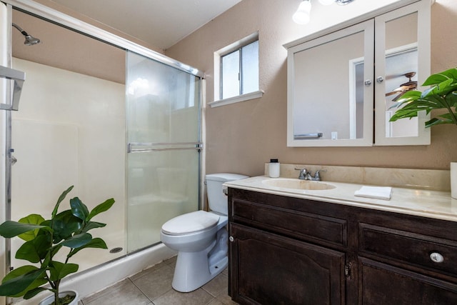 bathroom featuring toilet, a shower stall, vanity, and tile patterned floors