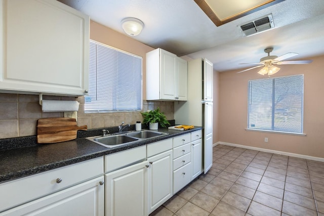 kitchen with dark countertops, visible vents, white cabinets, and a sink